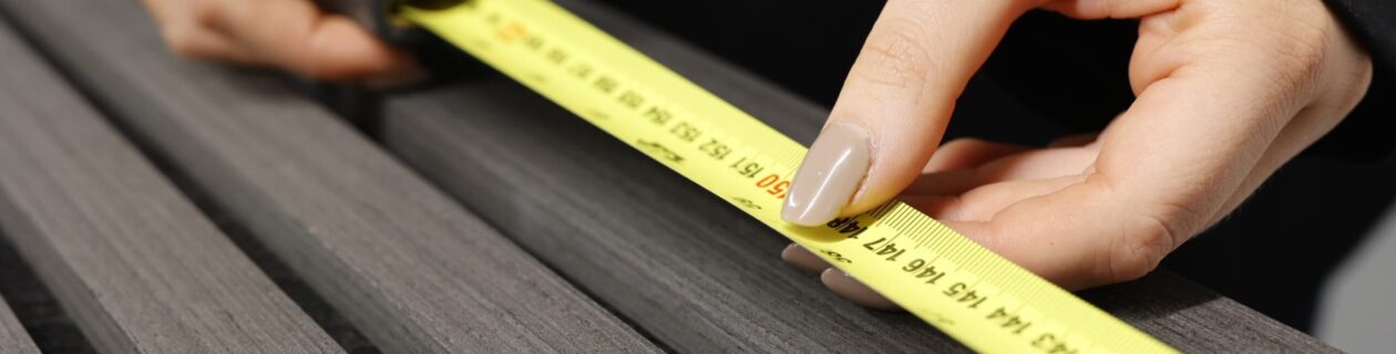 Hand Using Measuring Tape To Check Slat Wall Size For Installation